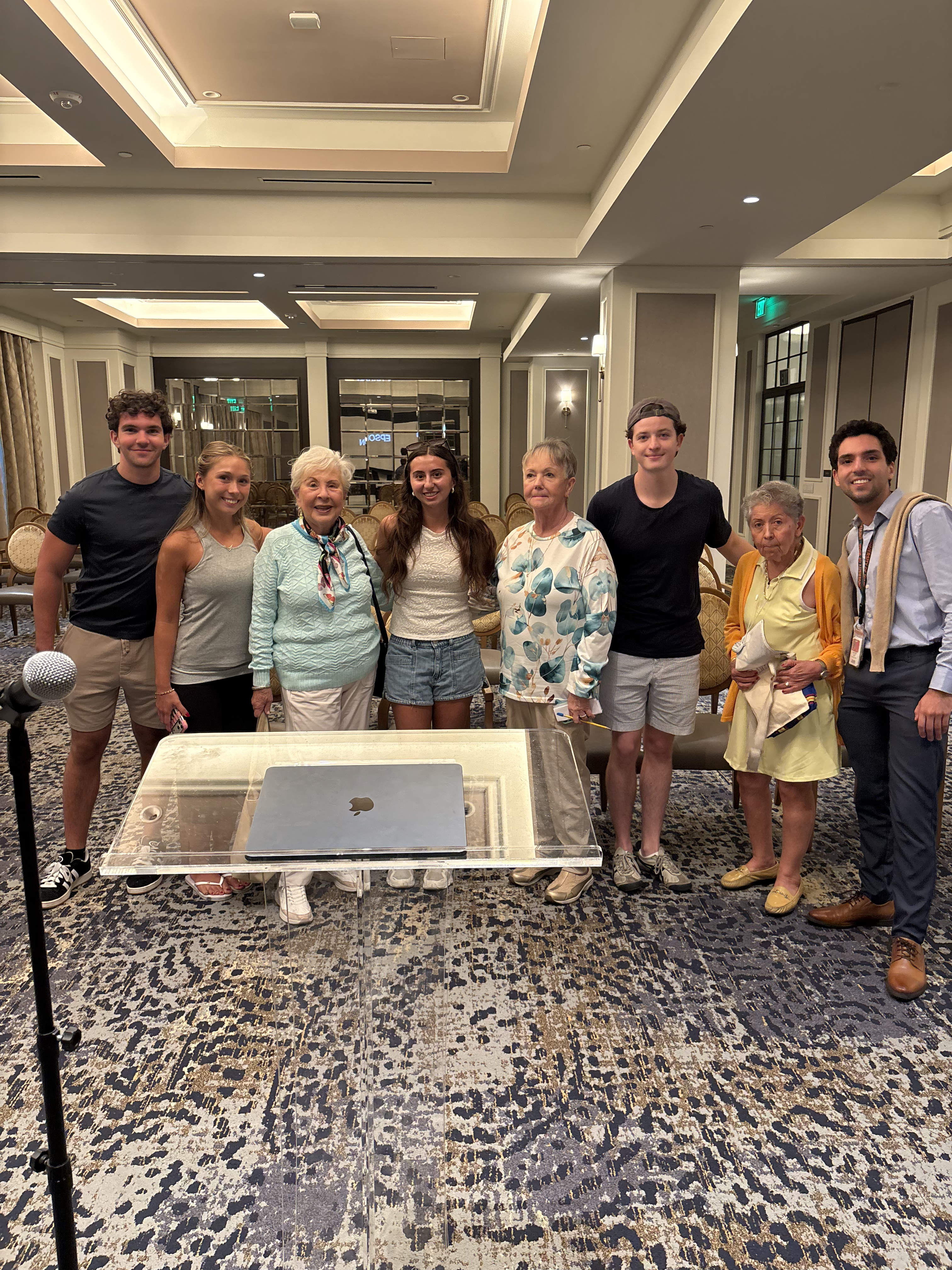 Tech Connect students and older adults standing together at the front of a community room after a technology workshop.
